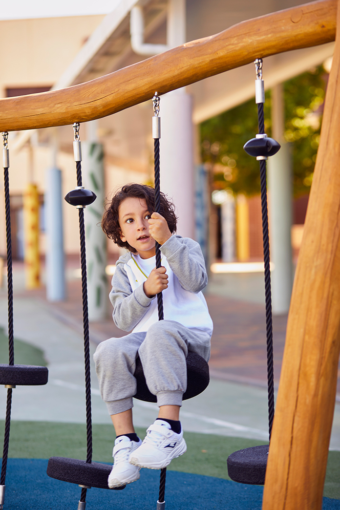 Boy wearing Joma Lion sweat-suit on a swing.