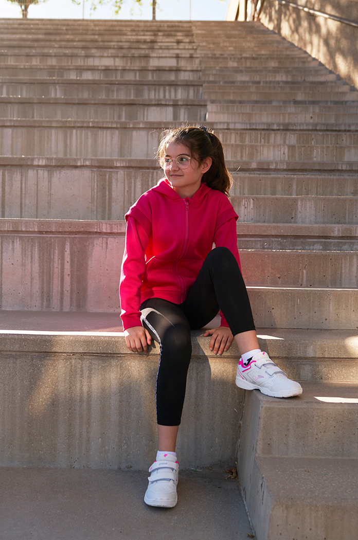 Bambina che indossa leggings Ascona di Joma seduta su una gradinata.