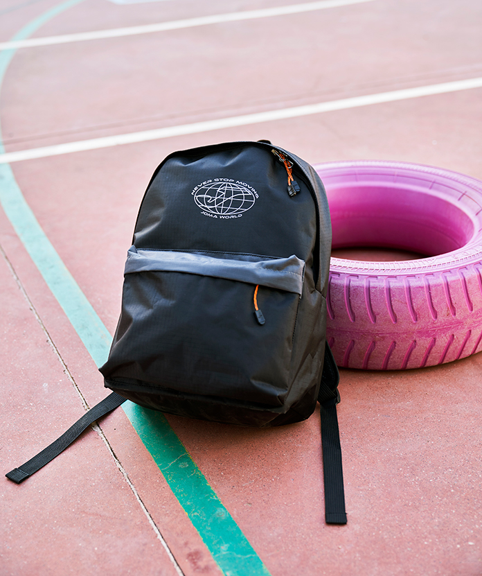 Joma Moving school back-pack leaning on a schoolyard.