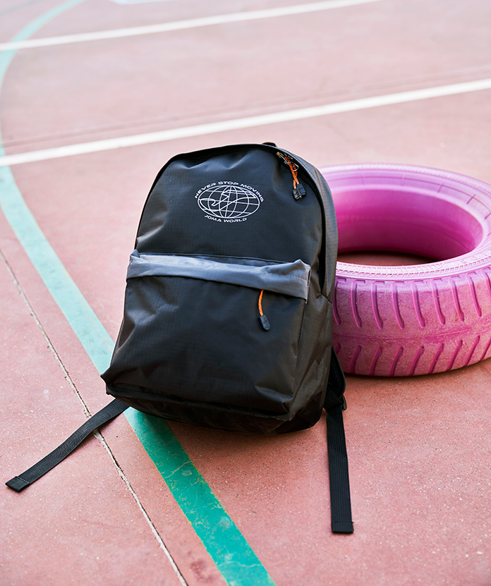 Mochila escolar Moving de Joma apoyada en la pista de juego del patio de un colegio.