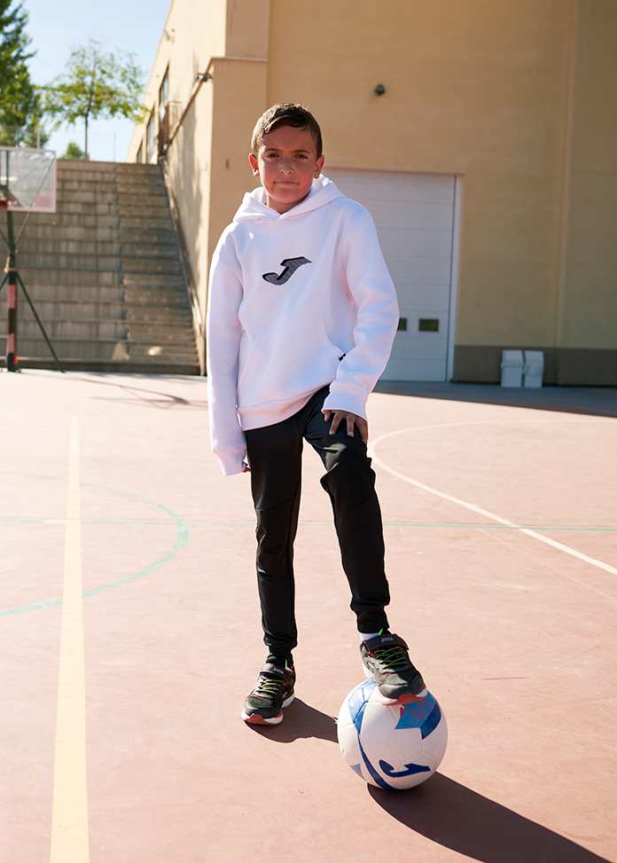 Chłopiec ubrany w szkolne spodnie dresowe Joma Lion na szkolnym boisku.