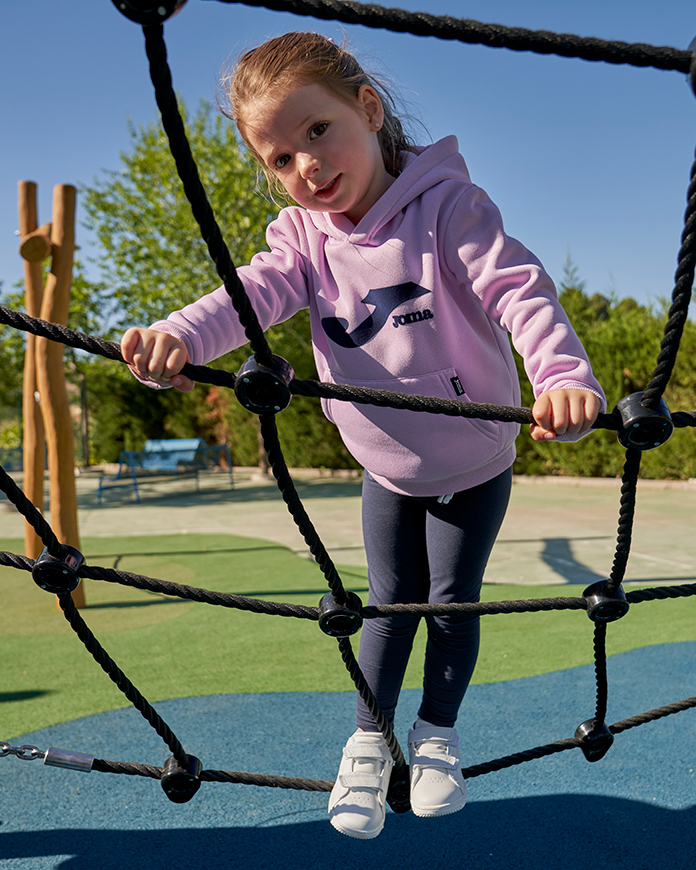 Menina com uma camisola Lion da Joma num parque. 