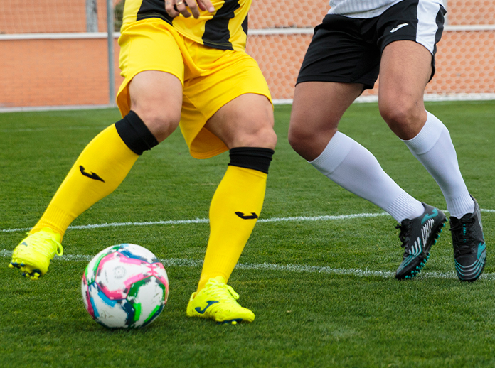 Futbolistas jugando al fútbol con botas de fútbol Joma.