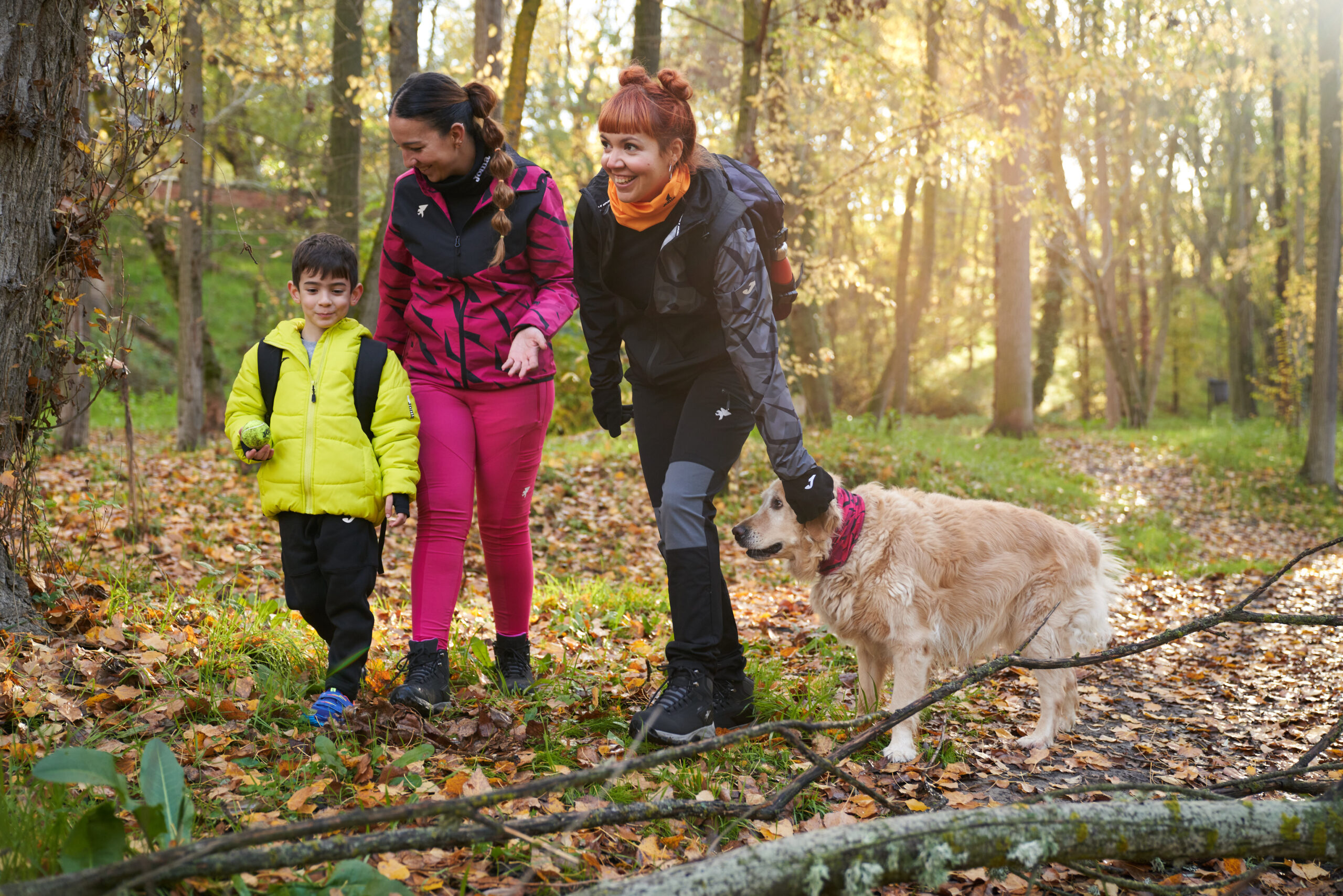 Dos chicas, un niño y un perro caminando por el monte.