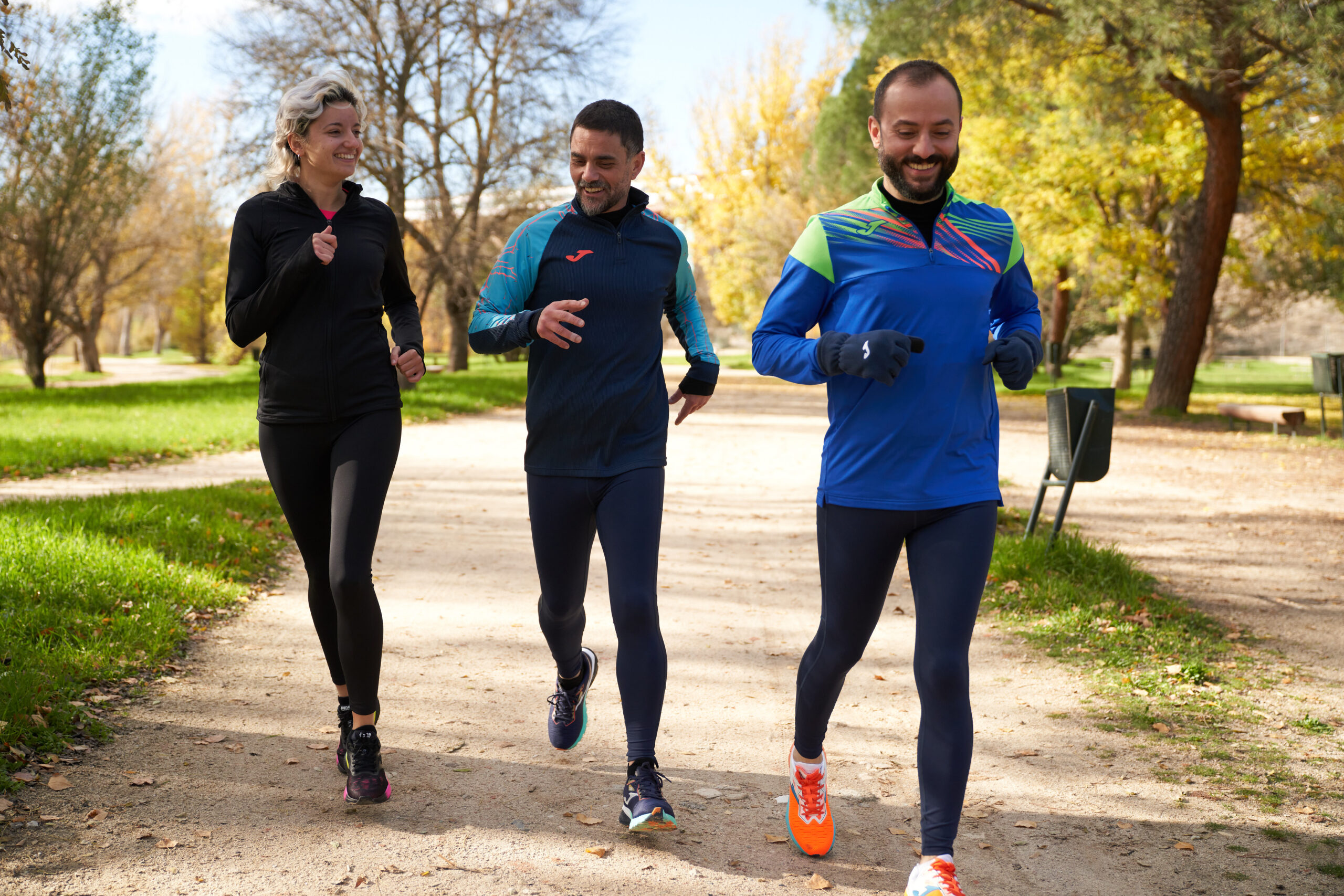 Chicos y chica corriendo por el parque y vistiendo producto Joma seleccionado para la campaña de Navidad.