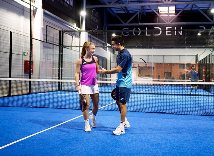 Un chico y una chica en una pista de pádel vistiendo producto Joma seleccionado para la campaña de Navidad.